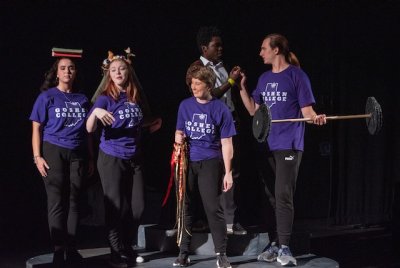 A small group of performers wearinng GC branded shirts interacts on stage.