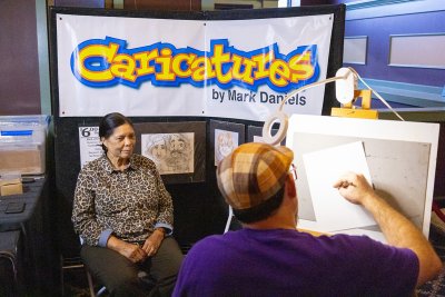 A woman sits for the caricature artist at Connectapalooza!