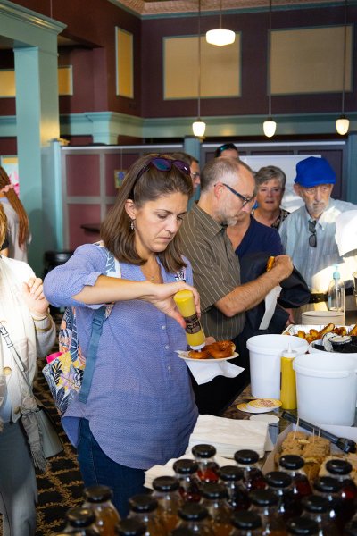 A woman adds mustard to her pretzel.