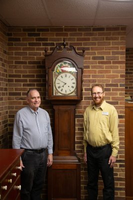 Joe Springer and Eric Bradley smile in front of an old clock in the MHL.