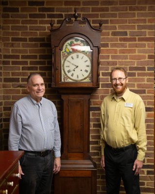 Joe Springer and Eric Bradley smile in front of an old clock in the MHL.